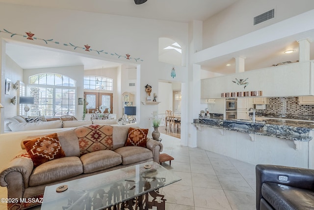 living area featuring visible vents and a towering ceiling