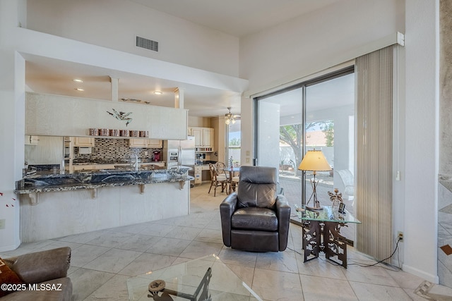 living area featuring a ceiling fan and visible vents