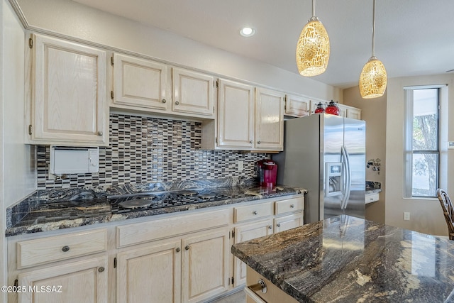 kitchen with stainless steel fridge with ice dispenser, decorative backsplash, dark stone countertops, and decorative light fixtures