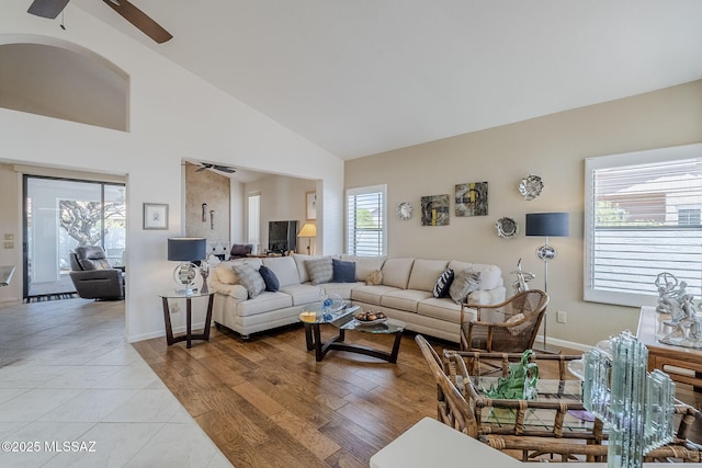 living area with baseboards, a ceiling fan, and high vaulted ceiling