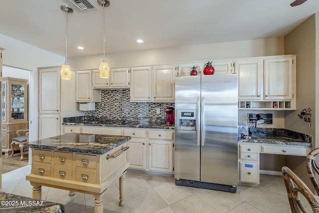 kitchen featuring black cooktop, stainless steel fridge with ice dispenser, dark stone countertops, backsplash, and visible vents