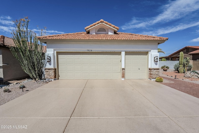 mediterranean / spanish-style home with an attached garage, stone siding, stucco siding, a tiled roof, and driveway