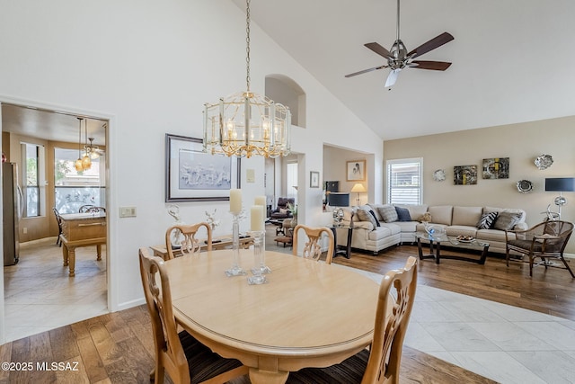 dining area featuring plenty of natural light, baseboards, ceiling fan with notable chandelier, and high vaulted ceiling