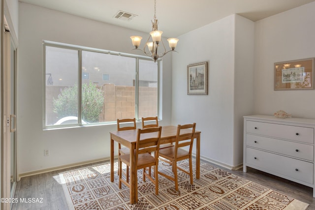 dining area featuring baseboards, a notable chandelier, wood finished floors, and visible vents