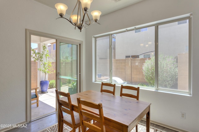 dining space featuring baseboards, an inviting chandelier, and wood finished floors