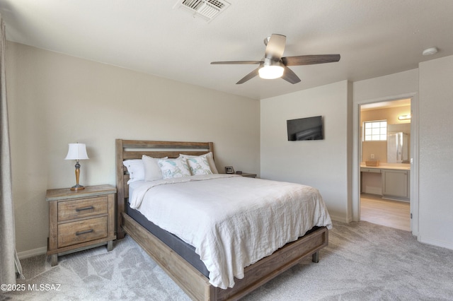 bedroom featuring baseboards, ensuite bathroom, light carpet, and visible vents