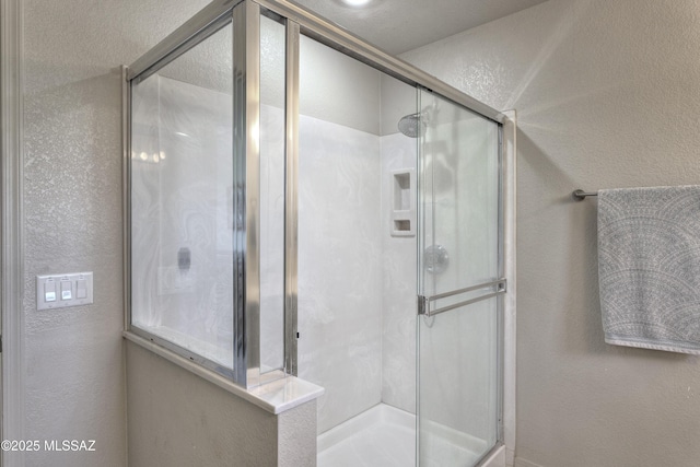 full bath featuring a textured wall and a shower stall