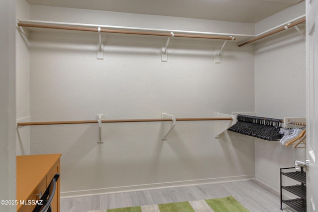 walk in closet with wood finished floors