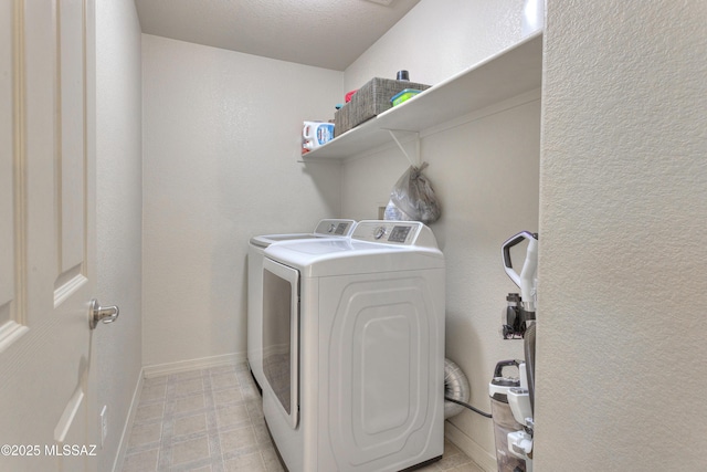 clothes washing area featuring laundry area, washing machine and dryer, and baseboards