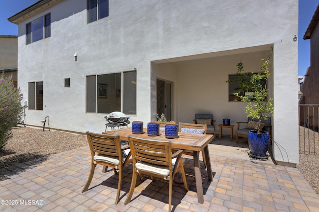 rear view of property featuring a patio, outdoor dining space, and stucco siding