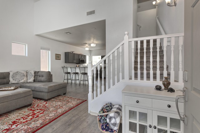 living area featuring visible vents, a towering ceiling, wood finished floors, and stairway