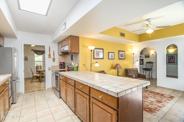 kitchen with a peninsula, visible vents, appliances with stainless steel finishes, under cabinet range hood, and light tile patterned floors