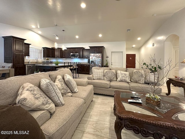 living area with arched walkways, vaulted ceiling, visible vents, recessed lighting, and marble finish floor