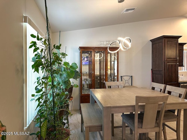 dining space featuring an inviting chandelier, vaulted ceiling, and visible vents