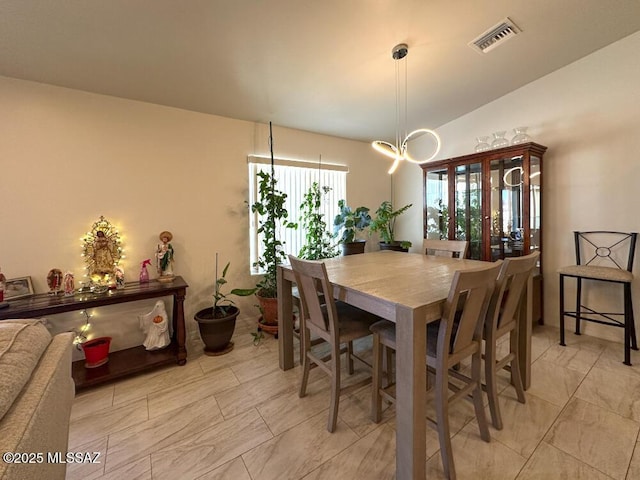 dining area with vaulted ceiling and visible vents