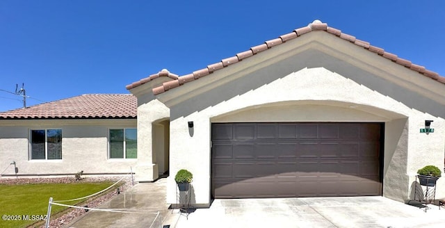 view of front of home featuring an attached garage, a tiled roof, and stucco siding