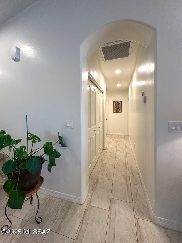 corridor featuring marble finish floor, arched walkways, visible vents, and baseboards