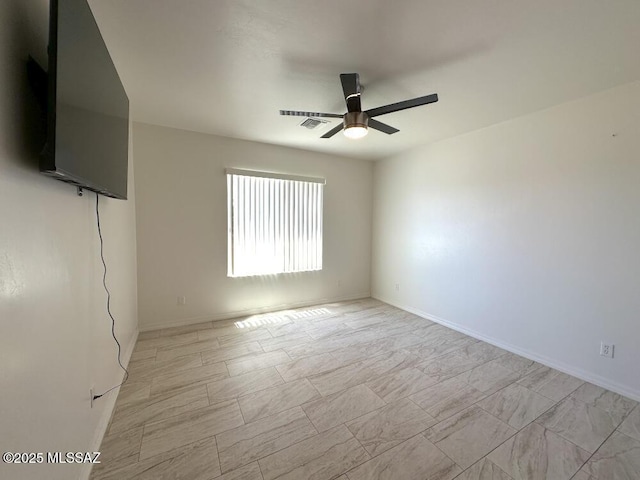 spare room featuring visible vents, a ceiling fan, and baseboards