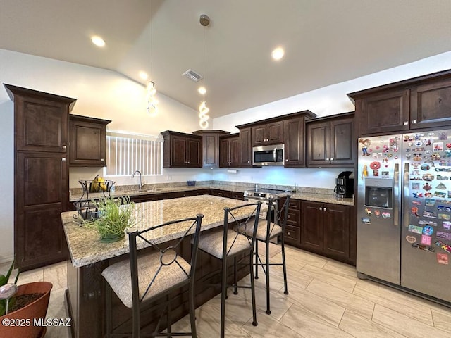 kitchen featuring dark brown cabinets, visible vents, a kitchen bar, lofted ceiling, and appliances with stainless steel finishes