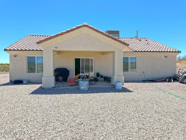 rear view of house with a tile roof, a patio area, and stucco siding