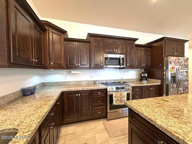 kitchen featuring dark brown cabinetry, appliances with stainless steel finishes, and light stone countertops