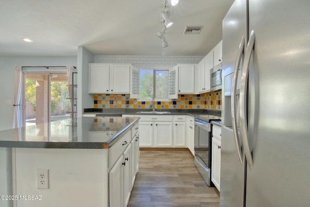 kitchen with a sink, range with electric cooktop, fridge with ice dispenser, rail lighting, and visible vents