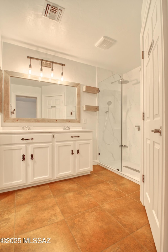 bathroom featuring visible vents, double vanity, a marble finish shower, and tile patterned floors