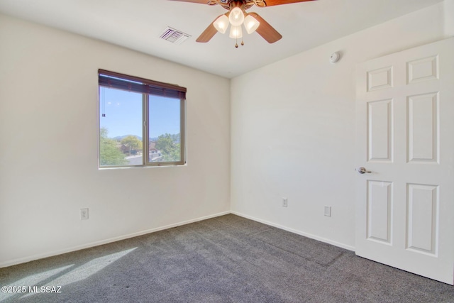 carpeted spare room with visible vents, baseboards, and ceiling fan