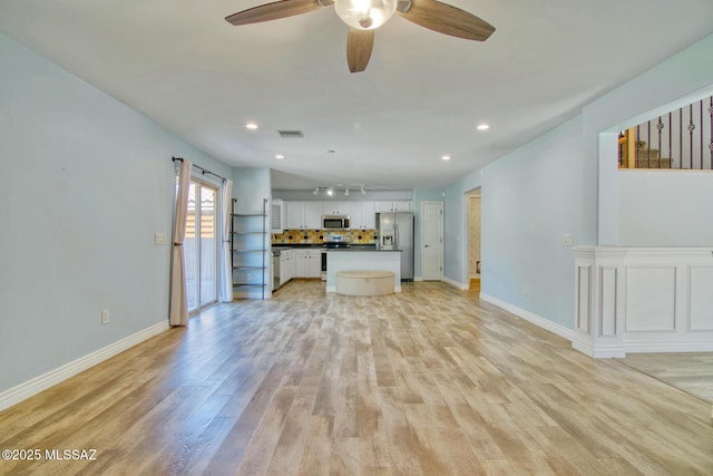 unfurnished living room with light wood finished floors, baseboards, a ceiling fan, and visible vents