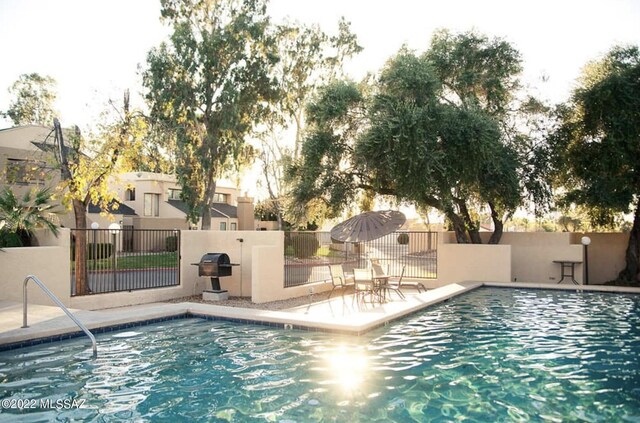 community pool with a grill, a patio, and fence
