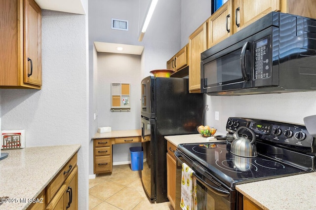 kitchen featuring light tile patterned floors, visible vents, brown cabinets, and black appliances