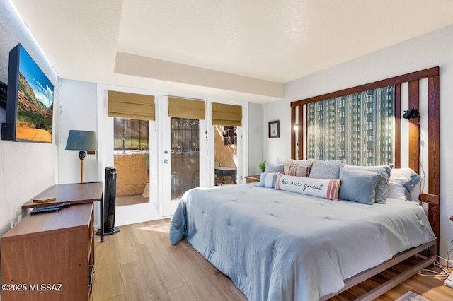 bedroom with french doors, light wood-style floors, and access to exterior