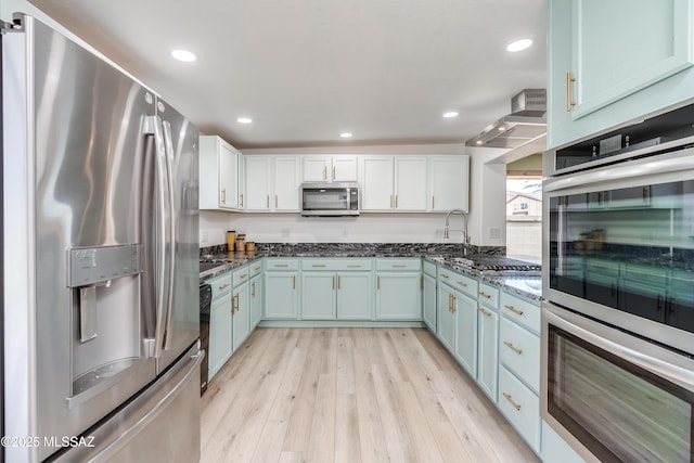 6624 N Galaxy Rd, Tucson, AZ 85741 - kitchen with light wood-style flooring, blue cabinetry, stainless steel appliances, and dark stone countertops