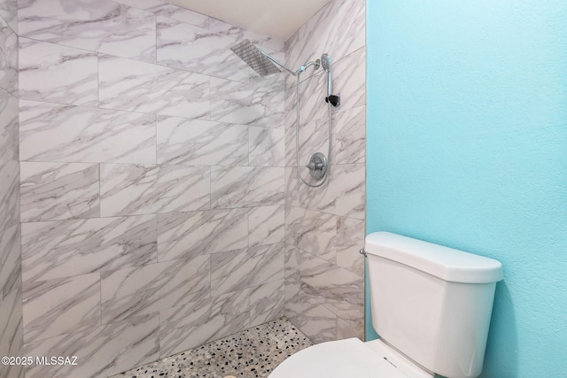 full bath with toilet and a tile shower
