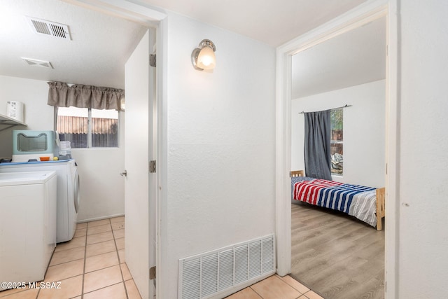 washroom with a wealth of natural light, visible vents, washer and clothes dryer, and laundry area