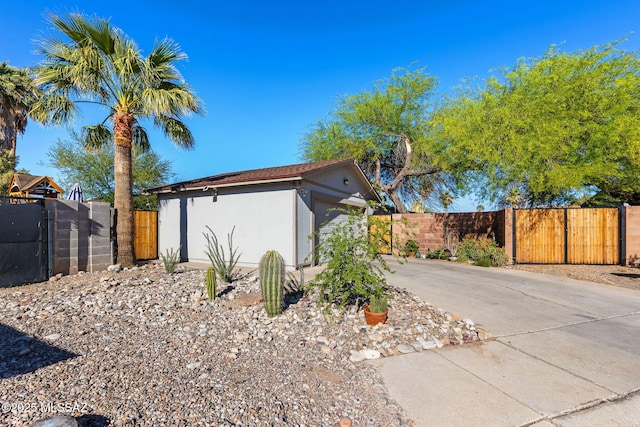 view of home's exterior with a gate, fence, an attached garage, driveway, and an outbuilding