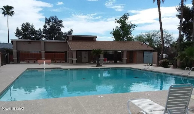 community pool with fence and a patio