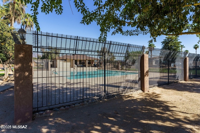 view of gate with fence, a community pool, and a patio
