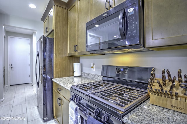 5854 W Indian Sunrise Dr, Tucson, AZ 85742 - kitchen with light stone countertops, black microwave, freestanding refrigerator, recessed lighting, and gas range oven