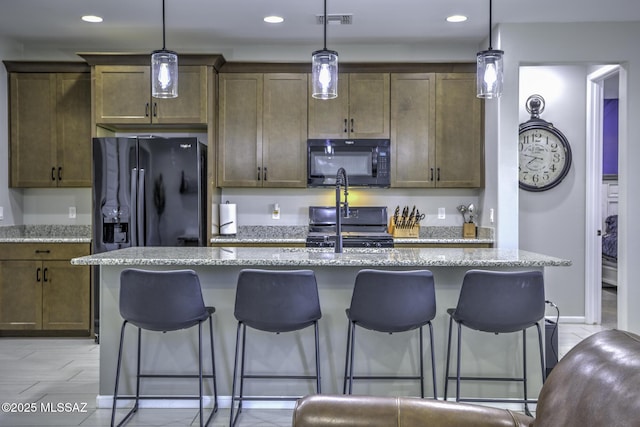5854 W Indian Sunrise Dr, Tucson, AZ 85742 - kitchen featuring visible vents, a kitchen breakfast bar, a kitchen island with sink, and black appliances