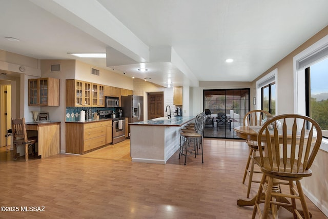 5122 W Camino De La Amapola, Tucson, AZ 85745 - kitchen featuring appliances with stainless steel finishes, a breakfast bar area, glass insert cabinets, a peninsula, and a sink