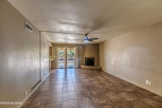 unfurnished living room featuring baseboards, visible vents, a ceiling fan, and a fireplace