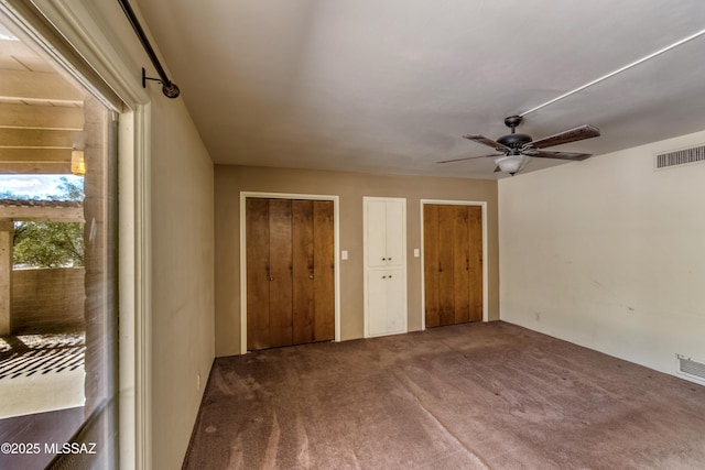 empty room with a ceiling fan, visible vents, and carpet floors