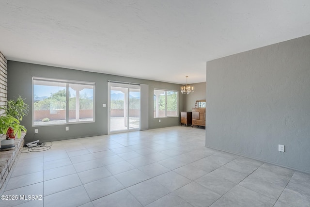 unfurnished living room with a textured wall, an inviting chandelier, and light tile patterned floors