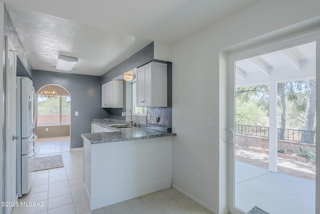 kitchen with baseboards, a sink, light tile patterned floors, and a notable chandelier