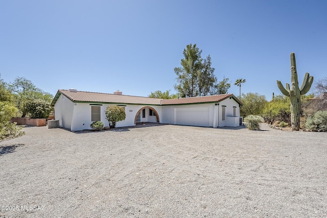 ranch-style home with a tiled roof, a garage, central AC unit, and a chimney