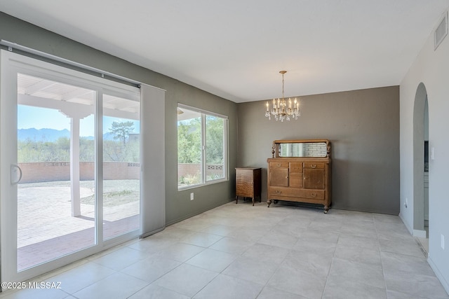 doorway to outside with visible vents, arched walkways, light tile patterned floors, baseboards, and a chandelier