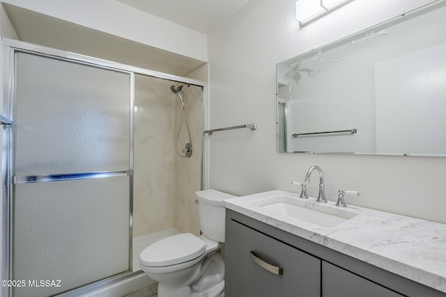 bathroom featuring toilet, a shower stall, and vanity