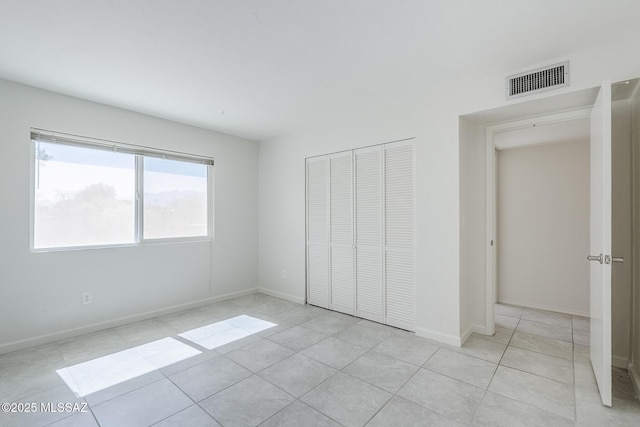 unfurnished bedroom featuring visible vents, baseboards, light tile patterned floors, and a closet