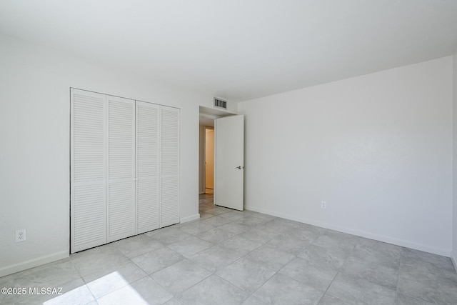 unfurnished bedroom featuring baseboards, a closet, and visible vents
